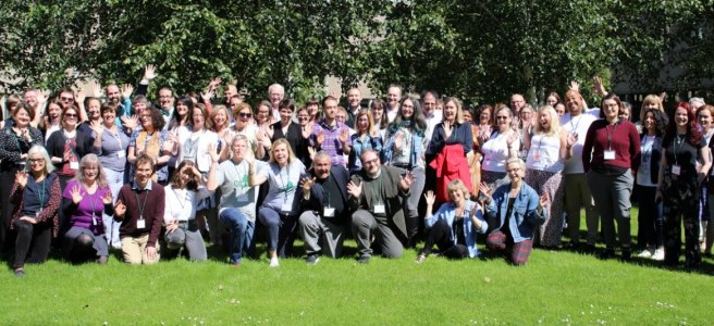 All attendees of the Icepops conference are standing outside under a tree and waving.