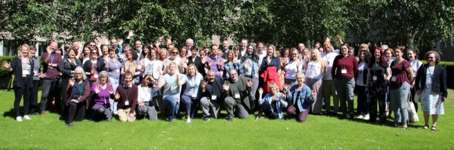 All attendees of the Icepops conference are standing outside under a tree and waving.